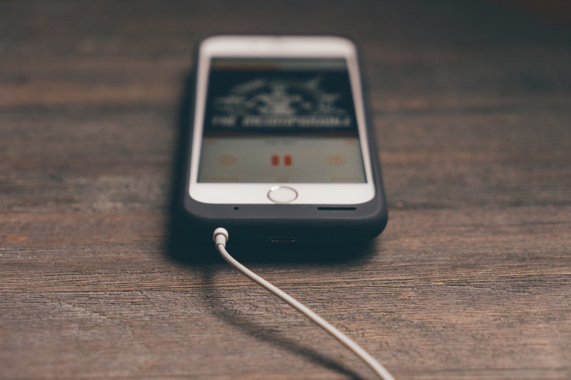 a white iphone with a music app on a wooden surface, playing music from a phone 4k