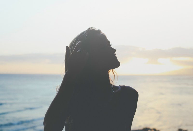 silhouette of a woman standing in the shadows near the ocean at sunset, ocean sunset silhouettes 4k
