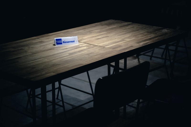 an empty table shrouded in darkness is lit up with a spotlight on a table card that reads reserved, _reserved empty table 4k