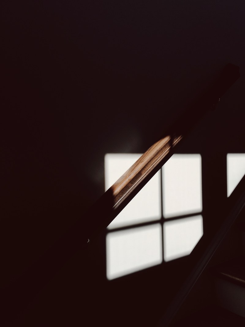 a dim shot of a wooden bannister illuminated by faint light from the window, dim wooden bannister 4k