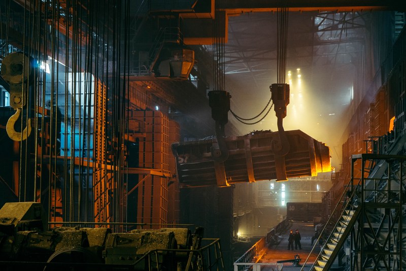 two men in a steelworks with a crane moving the material over their heads, busy day at the steelworks 4k