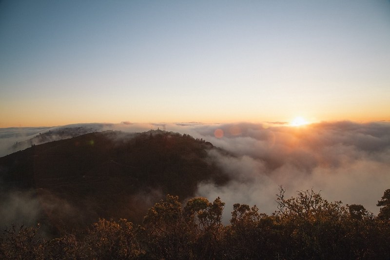 a scenic landscape with thick fog shrouding wooded hills during sunrise, sunrise over foggy hills 4k