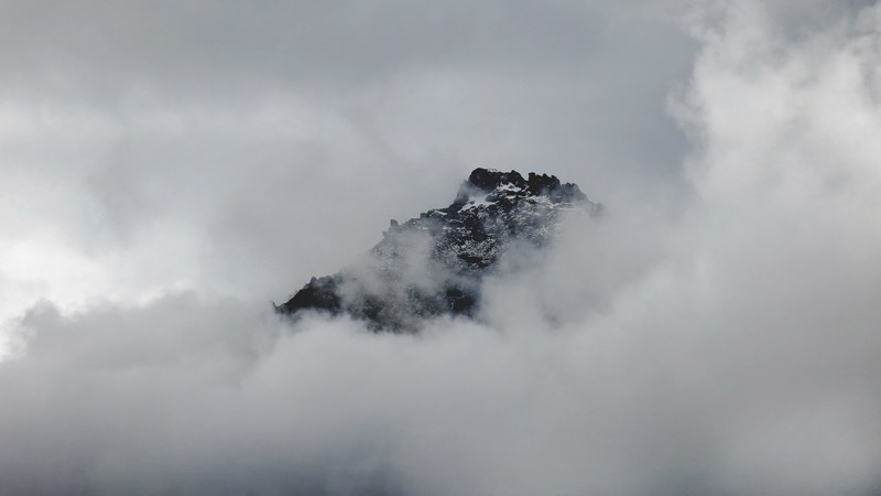 snowy mountain summer peeks through clouds in franz josef glacier, mountain summit through fog 4k