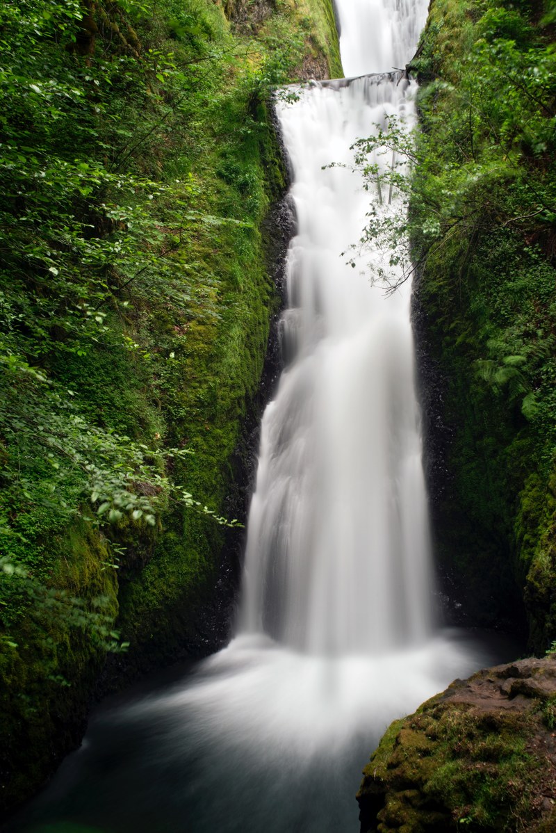 a frothy waterfall cascading down from a mossy rock face, green cascade in bridal veil falls 4k