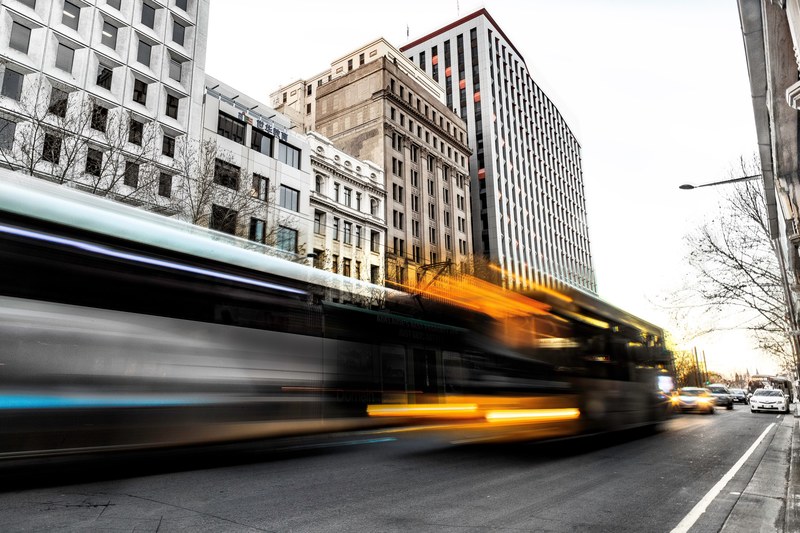 a long exposure shot of long bus and trolley silhouettes on a city street, rush hour 4k