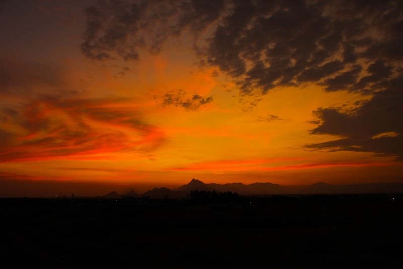 swirling clouds in a reg and orange sunset sky with silhouetted mountains in the distance, sunset love 4k