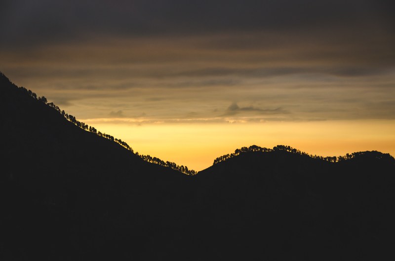 silhouette tree topped ridge from mount rinjani with a yellow sky that becomes cloudy and gray, silhouette ridge and yellow sky 4k