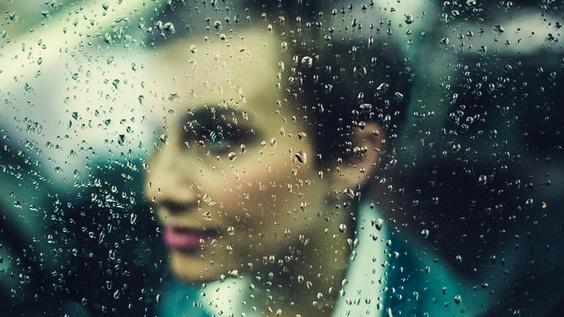 a womans face seen through a rain streaked window, woman behind a rainy window 4k