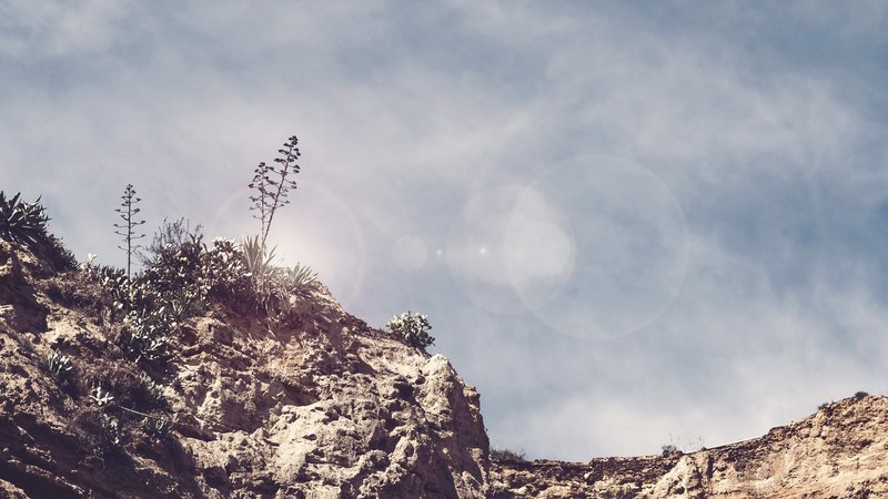 sun shine over a rocky mountain cliff against a blue sky, sunny mountain cliff 4k