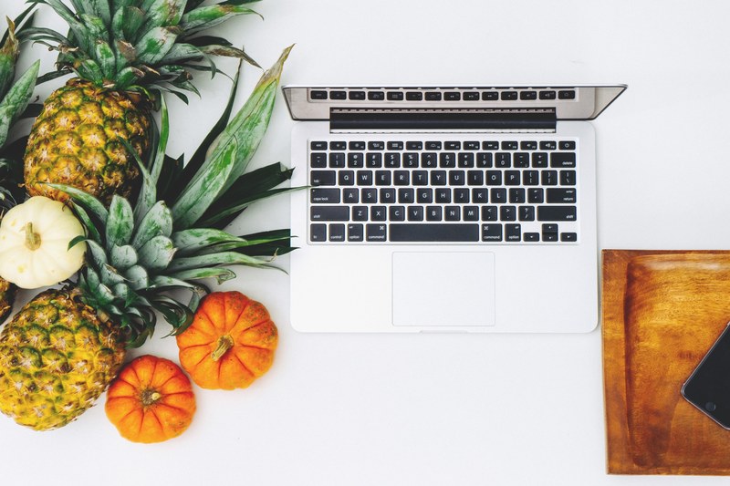 top view of pineapples and miniature pumpkins and a macbook, _macbook and culinary fruits in flatlay 4k