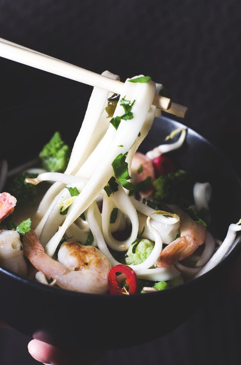 chopsticks pick up noodles from a bowl full of shrimp and herbs, eating asian noodles 4k