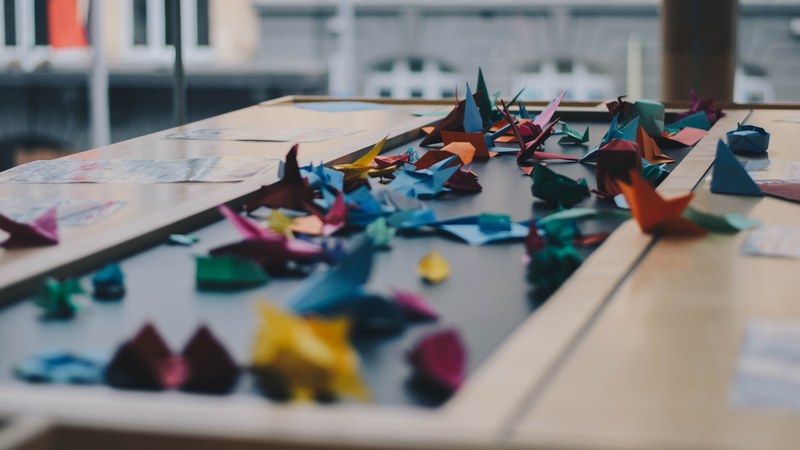 a large number of colorful origami cranes scattered across a table, paper crane table 4k