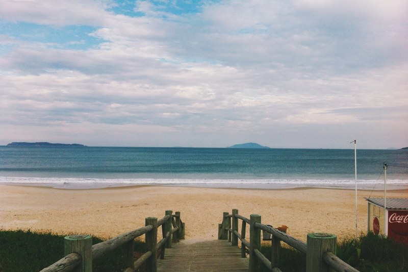 wooden path leading to the sandy beach on a cloudy day, sand beach by the ocean 4k