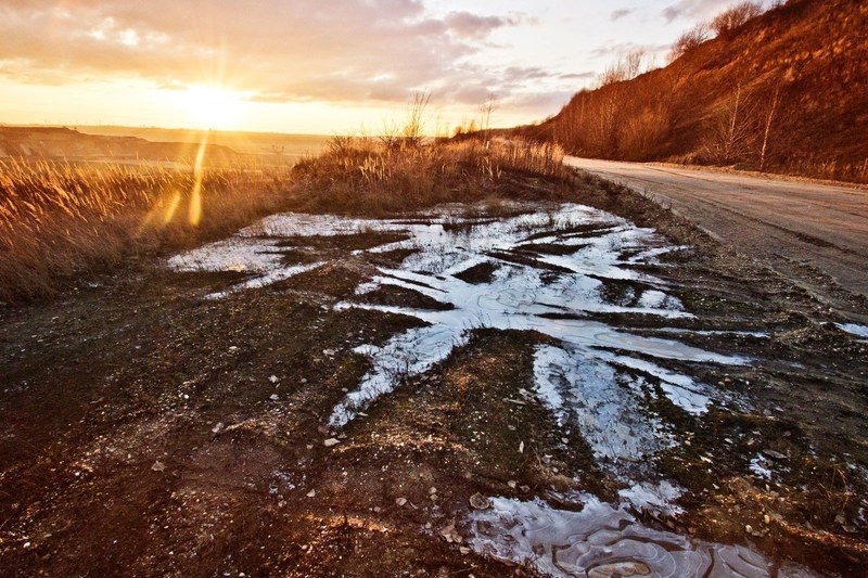 muddy field along the side of the road during as the sun sets in the horizon, muddy side of the road during sunset 4k