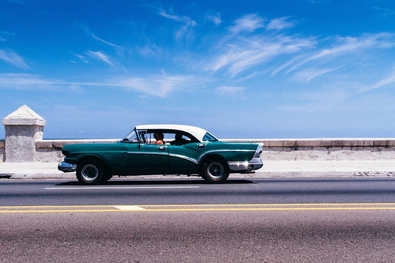 a vintage cadillac driving along a bridge, turquoise vintage car on a bridge 4k