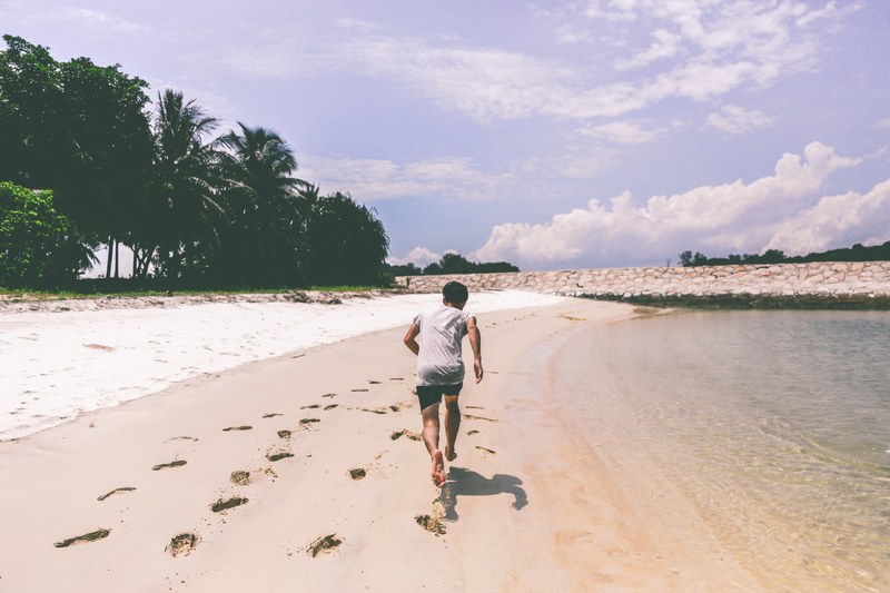 a person running on a beach and making footprints in the sand during low tide, running along the beach 4k