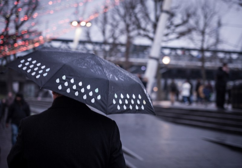a blurry shot of a man with a wet black umbrella in london, wet weekend 4k