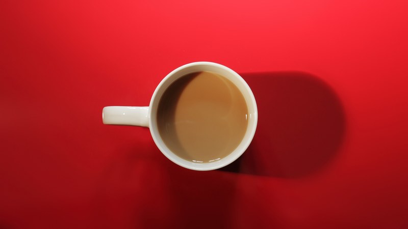 a top view of a half filled mug containing coffee in a red background, coffee mug in a red background 4k