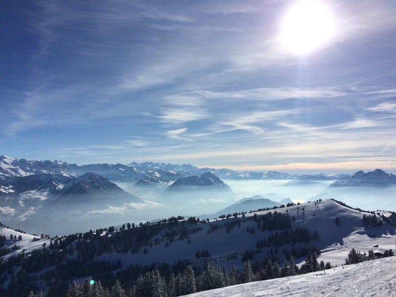 sun blazes down from blue sky among mountaintops trees and icy ground, winter sun over the mountains 4k