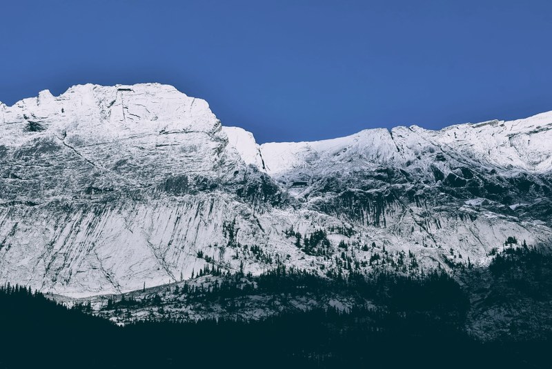 a tall steep mountain face against a blue sky in jasper national park, white mountain face in jasper 4k