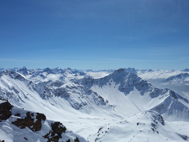 the top of a mountain completely covered in snow under a blue sky, snow covered mountain top 4k