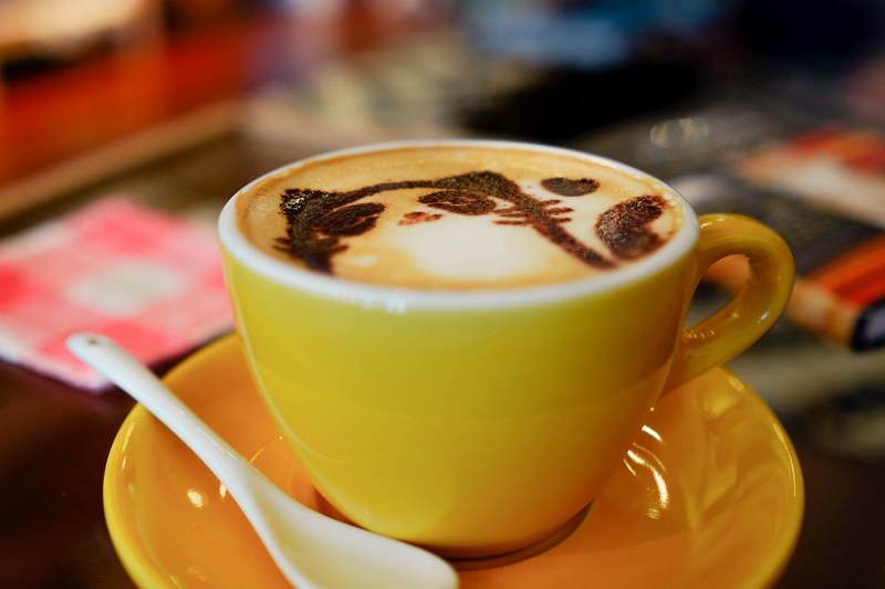 small cappuccino in a yellow mug on a yellow saucer with a spoon and cat shaped foam art, cat cafe 4k