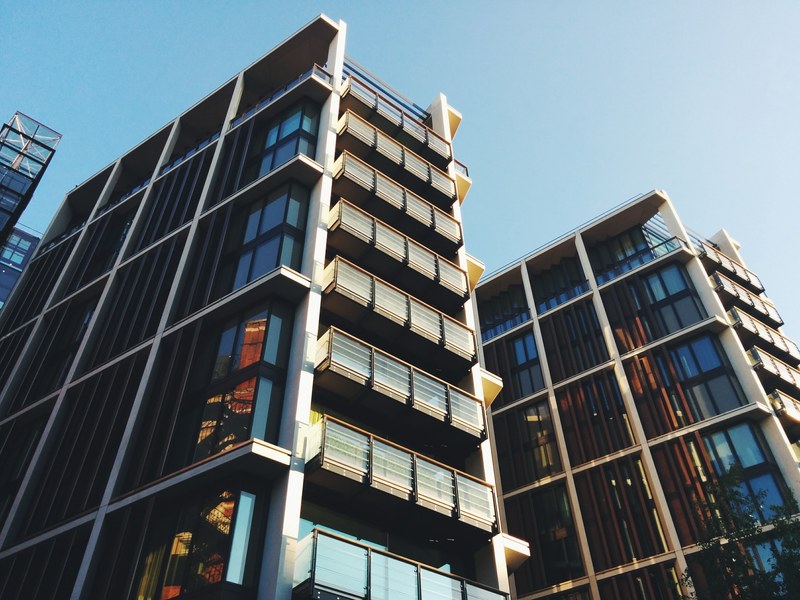 apartment buildings with unique architecture and balconies and windows under a blue sky, apartment building balconies 4k