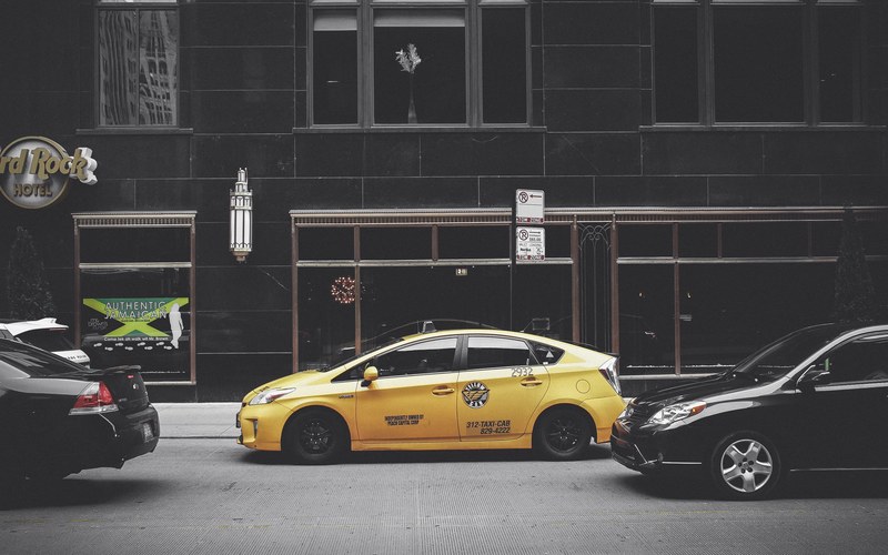 yellow taxi cab parked on a busy street by a dark building, pop the color 4k
