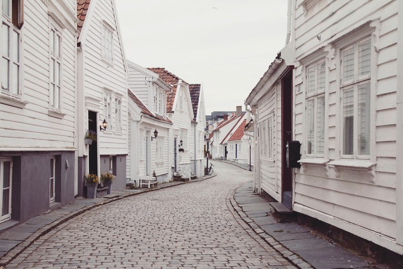 a curved street in a village with narrow sidewalks and one car lane, single lane village street 4k