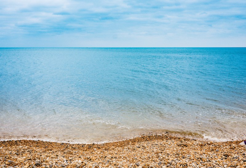 a brown sandy shoreline along a clear blue ocean in brighton, brighton beaches 4k