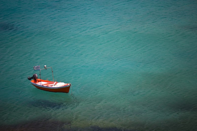 an orange boat with a greek flag flying floating on the sea, greek boat 4k