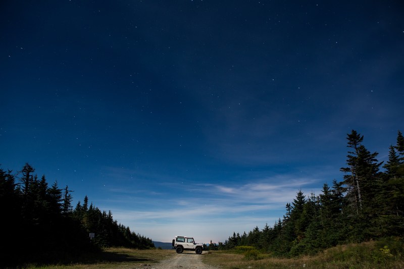 an off road vehicle parked across a dirt path in the forest in the evening, evening off road expedition 4k