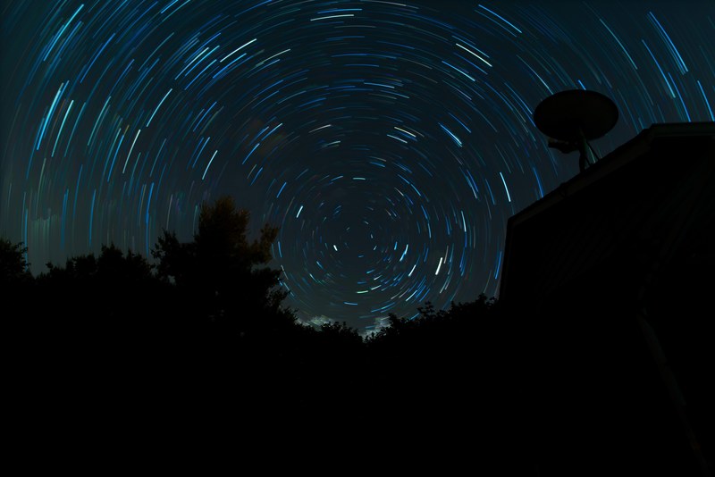 star trail above the silhouette of trees and rooftop, star trail trees rooftop 4k