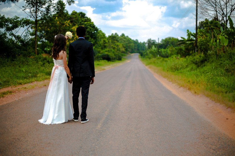 bride and groom hold hands on a rural road on a sunny day in mukono, bride and groom on rural road 4k
