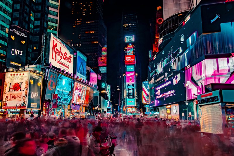 people walk quickly around the theater district of times square in new york city at night, city in motion 4k