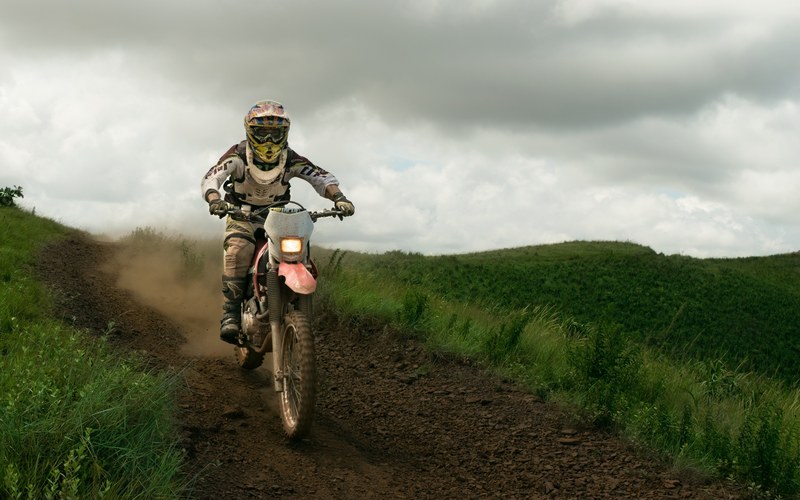 a motocross driver wearing protective gear and a helmet on a motorcycle in brumadinho, motorbike dirt road 4k
