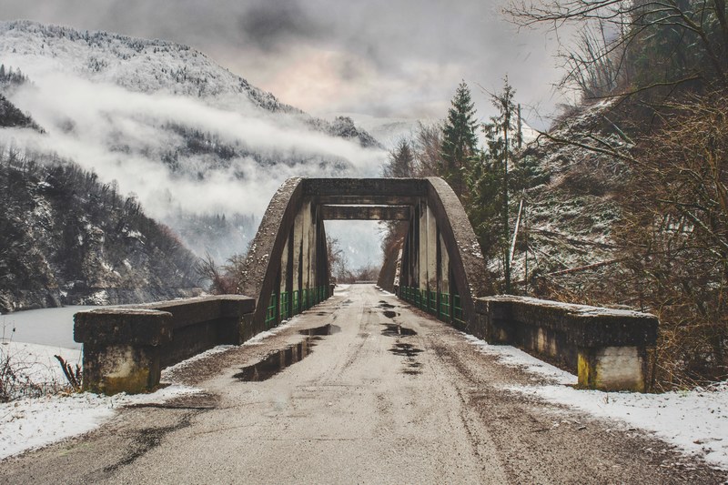 a concrete bridge in the snowy mountains near lago di corlo, old bridge in the mountains 4k