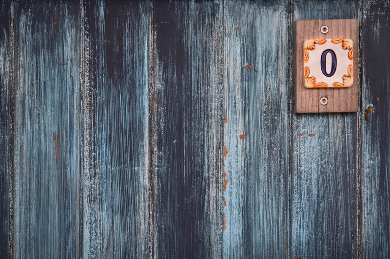 a weathered wooden wall with a small plaque with the number zero, zero 4k