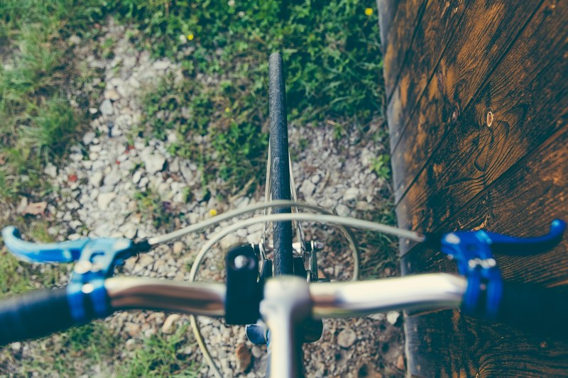 drone view of bicycle handlebars and brakes on gravel and grass near a wall, bicycle handlebars 4k