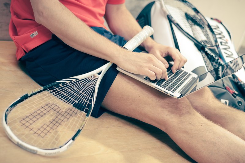 a man with a tennis racket on his lap working on a laptop, tennis player with a laptop 4k