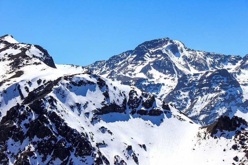 a snowy mountain peak in front of a vivid blue sky, snowcap mountains in the sky 4k