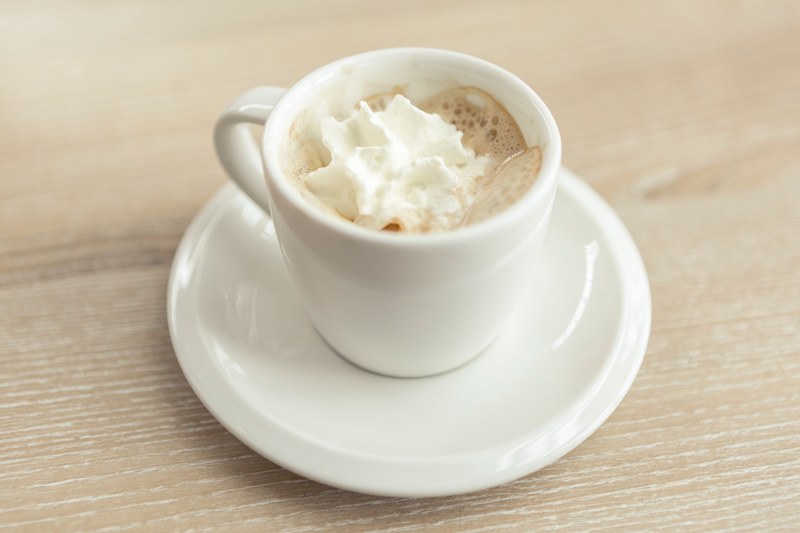 espresso with whipped cream in a white mug on a white saucer with a light wooden table underneath, espresso with whipped cream 4k