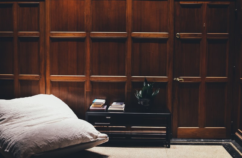 a black coffee table and a pillow chair next to a wall with wooden panelling, coffee table by a wooden wall 4k