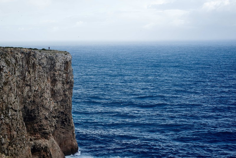a rocky cliff overlooking a brilliant blue sea at sagres, rock over the sea 4k