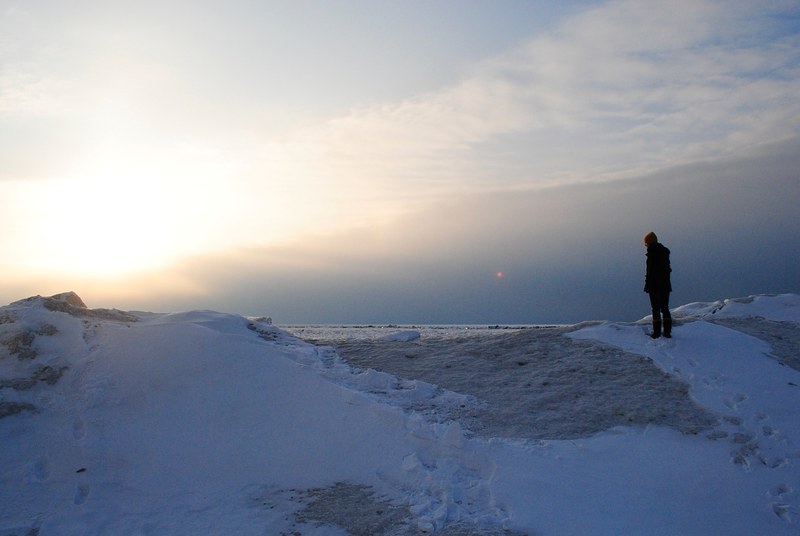 lone hiker stands atop a snowy mountain in a sunny winter landscape, man in snowy hills 4k