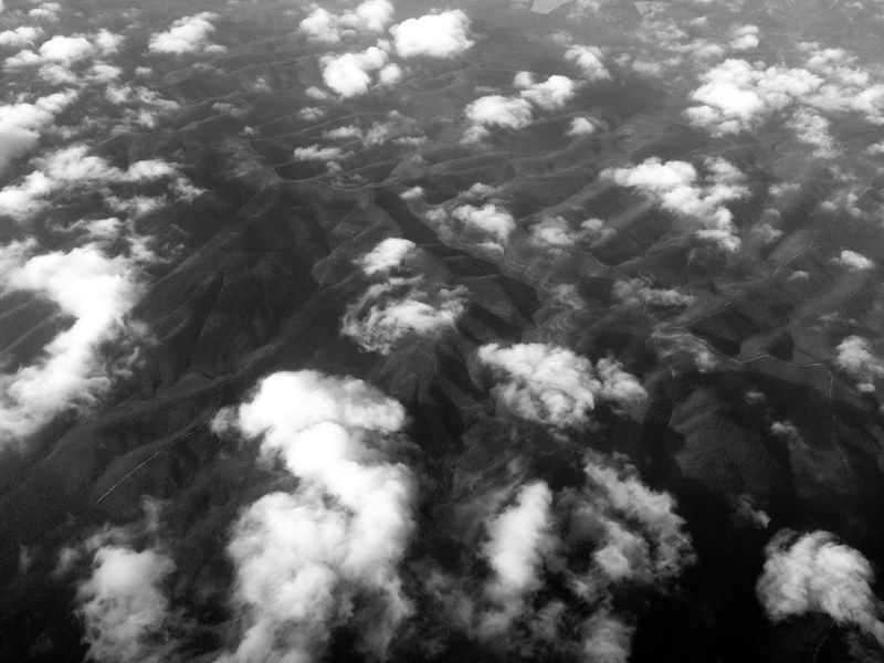 black and white drone shot of clouds over mountain range in nuevo leon, mountain folds in black and white 4k