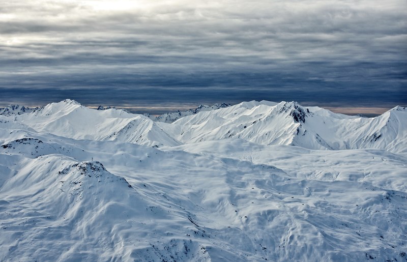 snow on mountains and plains under cloudy skies, dark clouds gathering over white mountains 4k