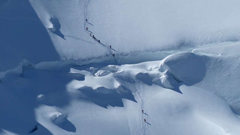 aerial view of a cross country hiking group walking across a snowy mountain trail, hiking across a mountain trail 4k