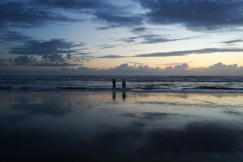two people standing on the beach looking out into the ocean at the horizon during sunset, man beach ocean horizon 4k