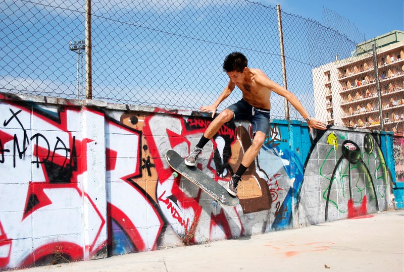 boy in the air on skateboard near graffiti and apartment buildings, boy on skateboard graffiti 4k